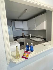 a kitchen with a counter with bottles and a book at Espacio2,1a línea,jacuzzi,piscina in Cullera