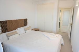 a white bed in a white room with a door at Espacio2,1a línea,jacuzzi,piscina in Cullera +22 photos