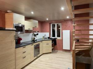 eine große Küche mit Holzschränken und schwarzen Arbeitsplatten in der Unterkunft Charme et quiétude au cœur du Haut-Jura in Lamoura