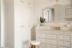 a white bedroom with a white dresser and a mirror at Ambelas Mare Apartments in Ambelas