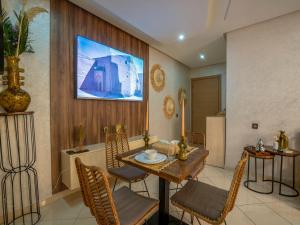una sala da pranzo con tavolo, sedie e televisione di Aliya Luxury Apartment - CORAIL - AGADIR ad Agadir Altre 32 foto
