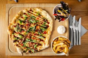 a pizza on a tray next to a bowl of fries at The Kellbank in Gosforth