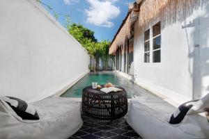 a pool with a table and chairs next to a building at Villa Maison Pastis Canggu in Canggu