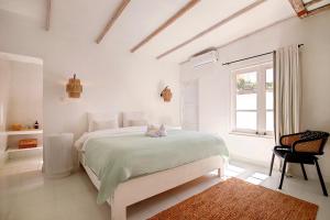 a white bedroom with a large bed and a window at Villa Maison Pastis Canggu in Canggu