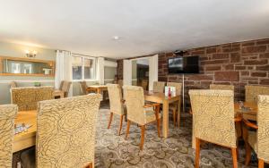 a dining room with tables and chairs and a brick wall at The Kellbank in Gosforth