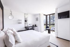 a white bedroom with a bed and a desk at L'Agapa Hôtel - Spa Codage in Perros-Guirec