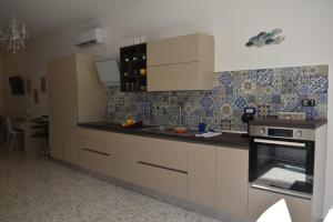 une cuisine avec des armoires blanches et un four à plaques de cuisson dans l'établissement Calipso casa vacanza, à Marina di San Vito