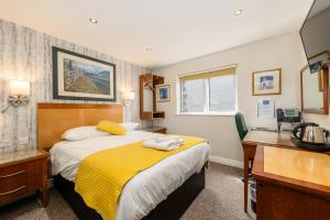 a bedroom with a bed and a desk with a telephone at The Kellbank in Gosforth