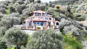 a pink house on top of a hill with trees at La Finestra sulle Eolie in Reitano