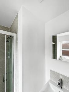 a white bathroom with a shower and a sink at Amaya Seven - Luxury 3 bedroom detached house with garden & driveway - Sleeps 7 - Bottesford, Leicestershire in Bottesford