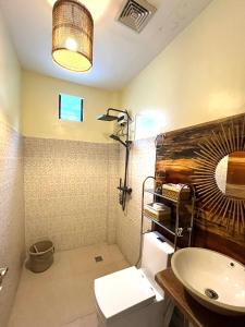 un bagno con lavandino, WC e specchio di Cozy Bungalow Isa with AC and Generator in General Luna a General Luna