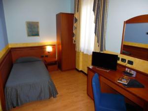 a room with a bed and a desk with a computer at Hotel Majestic in San Giuliano Milanese