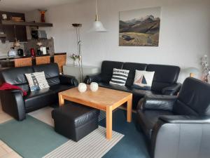 a living room with black leather couches and a wooden table at Appartment 142 in Tossens in Tossenserdeich