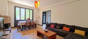a living room with a couch and a table at Maison "La Fleur d'oranger" climatisée, classée 3 étoiles, jardin clos, box internet in Saint-Féliu-dʼAmont