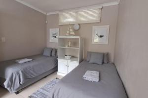 a bedroom with two beds and a white shelf at The Wooden Anchor spacious and modern in Zinkwazi Beach +40 photos