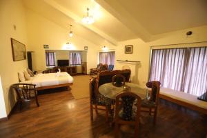 un soggiorno con un letto, un tavolo e delle sedie di Tiger Hill Homestay a Ooty