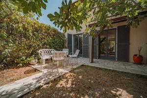 a patio with a table and chairs in front of a house at Belle maison et jardin à Pessac 10 pers in Pessac