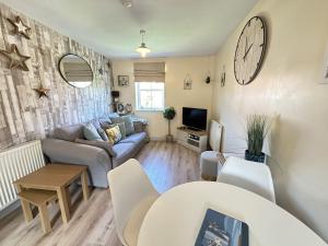 a living room with a couch and a clock on the wall at Starfish Shack - Part of the The Bay Filey Holiday Village with pool, gym and direct beach access, pub, restaurant, tennis and meadows walks in Filey