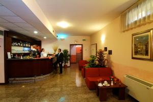 a lobby with a bar and people standing at a counter at Hotel Majestic in San Giuliano Milanese