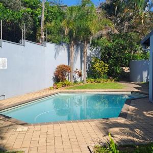 a swimming pool in a yard next to a white wall at The Wooden Anchor spacious and modern in Zinkwazi Beach