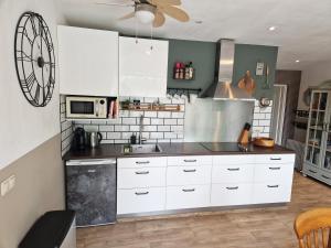 a kitchen with white cabinets and a clock on the wall at Bed & Bentwoud in Benthuizen