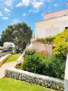 Biały dom ze ścianą i krzakami w obiekcie Apartamento Lia en Port Addaia, piscina y barbacoa, perfecto para vacaciones w mieście Port d'Addaia
