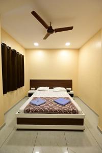 a bedroom with a bed and a ceiling fan at Aasra Lodge in Ratnagiri +7 photos