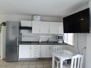 a kitchen with white cabinets and a table and a refrigerator at La Sirena in La Restinga