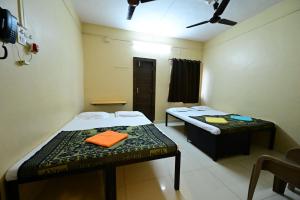 a room with two beds and a table in it at Aasra Lodge in Ratnagiri
