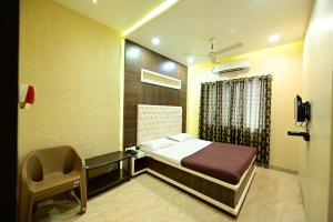 a bedroom with a bed and a chair in it at Aasra Lodge in Ratnagiri