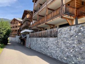 a building with a stone wall with a balcony at Apartment A304 La Perle de Savoie in Châtel
