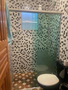 a bathroom with a glass shower with a toilet at Braga Café & Hospedagem in Sêrro