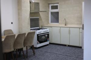a kitchen with a stove and a sink and chairs at Besan Motel in As Sulaymānīyah