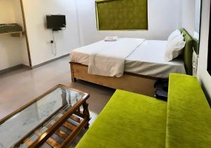 Shivansh Cottage Diveagar في دايف إيغار: غرفة بسرير واريكة خضراء
