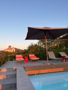 a patio with an umbrella and chairs and a pool at Casa Dr Ramiro Salgado - Douro Superior, Torre de Moncorvo in Torre de Moncorvo