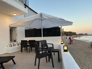 a table with chairs and an umbrella on the beach at Seaside Luxury Komi Beach Villa in Kómi