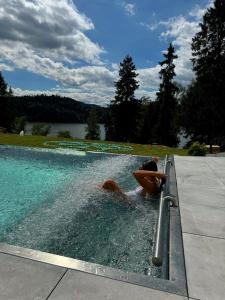 a person sitting in a swimming pool in a fountain at Czorsztyn Prestige Osada - luksusowe apartamenty dla dorosłych i dzieci od 12 lat in Czorsztyn