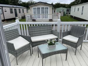 a group of chairs and a table on a deck at The Thimble static Holiday Home in Lancaster