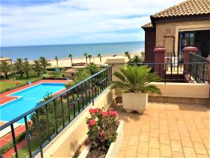 a balcony of a house with a swimming pool and the beach at Alcaudón, Isla Canela - By AC REAL in Isla Canela