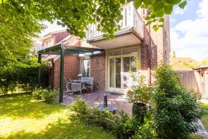 a patio of a brick house with an awning at Up Besöök - Wildrose mit Sauna in Krummhörn