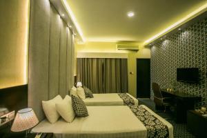 ein Hotelzimmer mit zwei Betten und einem Fernseher in der Unterkunft Tropical Daisy - Lake View in Dhaka
