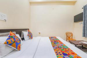 una camera da letto con un letto bianco con cuscini colorati di FabExpress Saryu a Ayodhya