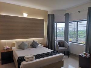 ein Schlafzimmer mit einem Bett, einem Stuhl und einem Fenster in der Unterkunft Tropical Daisy - Lake View in Dhaka