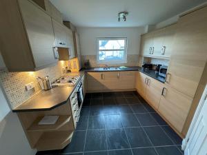 a kitchen with wooden cabinets and a black tile floor at Kingfisher Apartment in Dunfermline