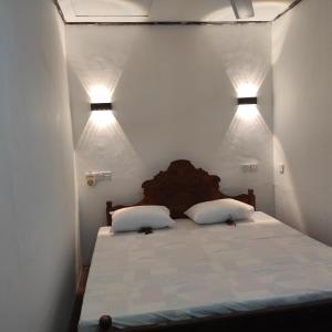a bedroom with a bed with two pillows and two lights at Asal Villa in Walliwala East