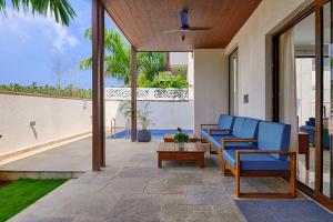 アンジュナにあるMelhor Stays Villa - L-M107 Luxury 4BHK villa with Private pool, Anjunaの青い椅子とテーブル付きのパティオ