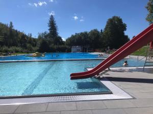 a slide in a swimming pool with people in the water at Ferienwohnung Schneemann in Hohegeiß