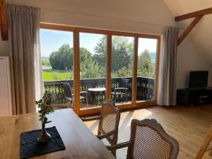 ein Wohnzimmer mit Tisch und Stühlen und einem Balkon in der Unterkunft Aich22 in Peißenberg + 33 Fotos
