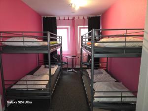 two bunk beds in a room with pink walls at Paulibude in Hamburg