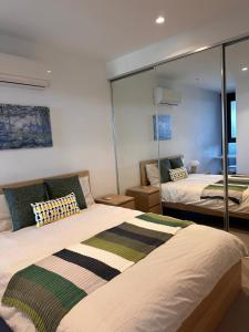 a bedroom with two beds and a mirror at Skyview Retreat Whitehorse Tower in Box Hill +24 photos